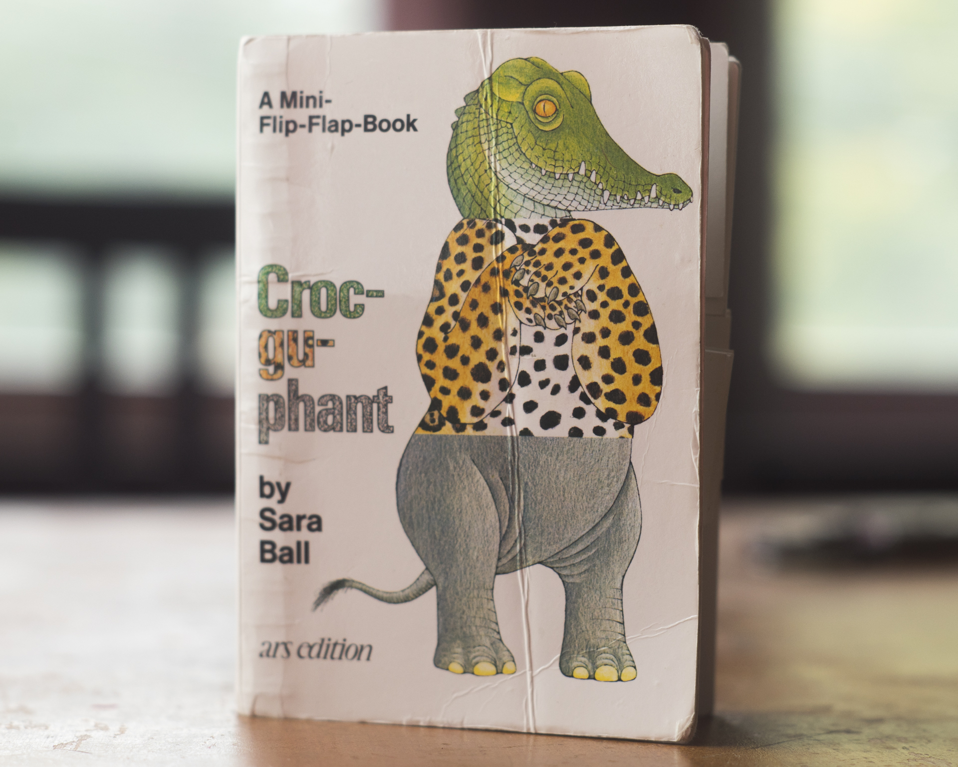 A photo of the Mini-Flip-Flap-Book 'Croc-gu-phant' by Sara Ball sitting upright on a wooden table
